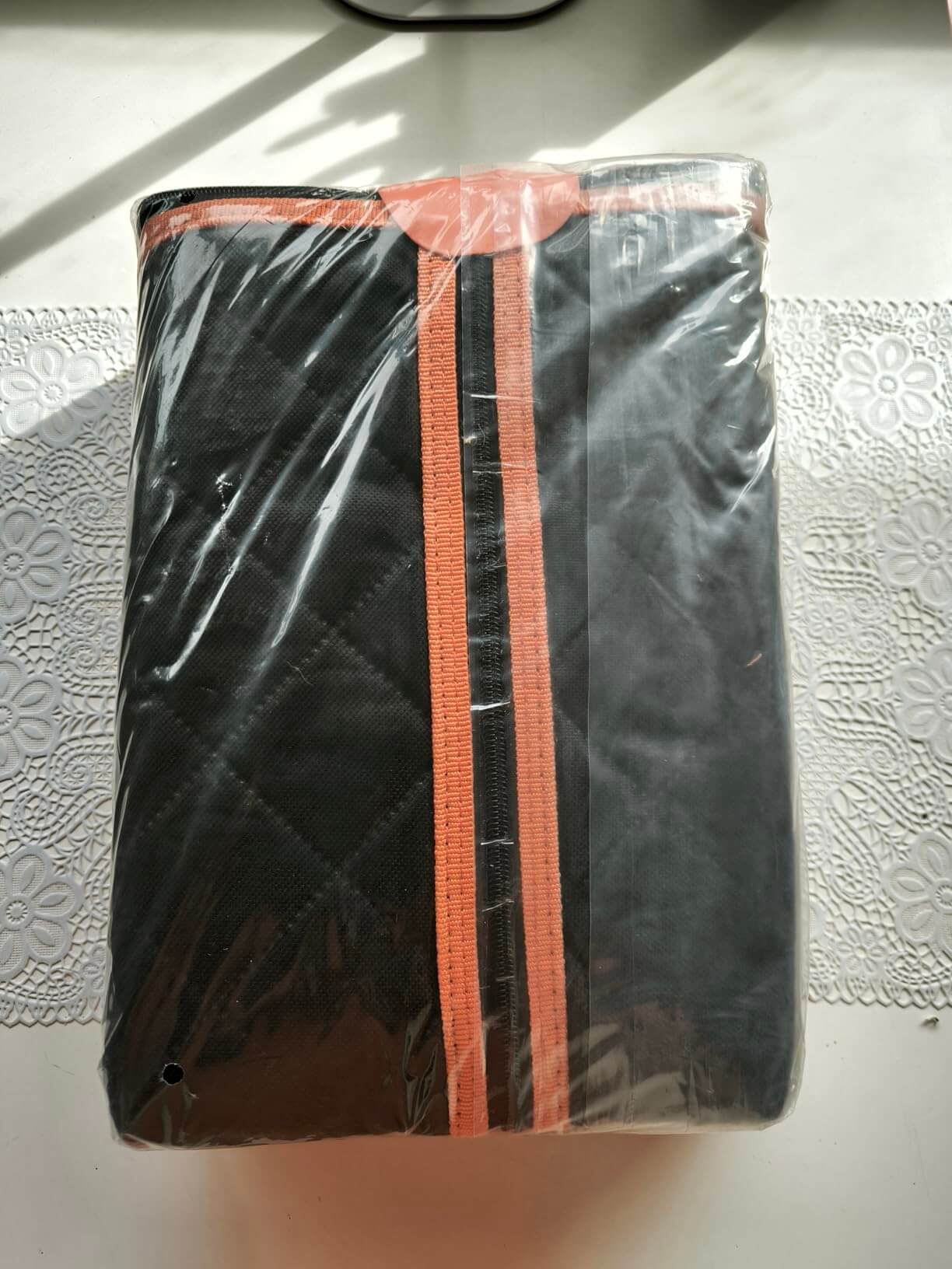 Black bag with orange car seat protector on a white surface